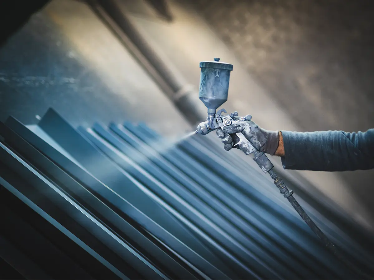 Poedercoaten van metalen profielen met een spuitpistool in de werkplaats van Ten Bolscher Poedercoating.